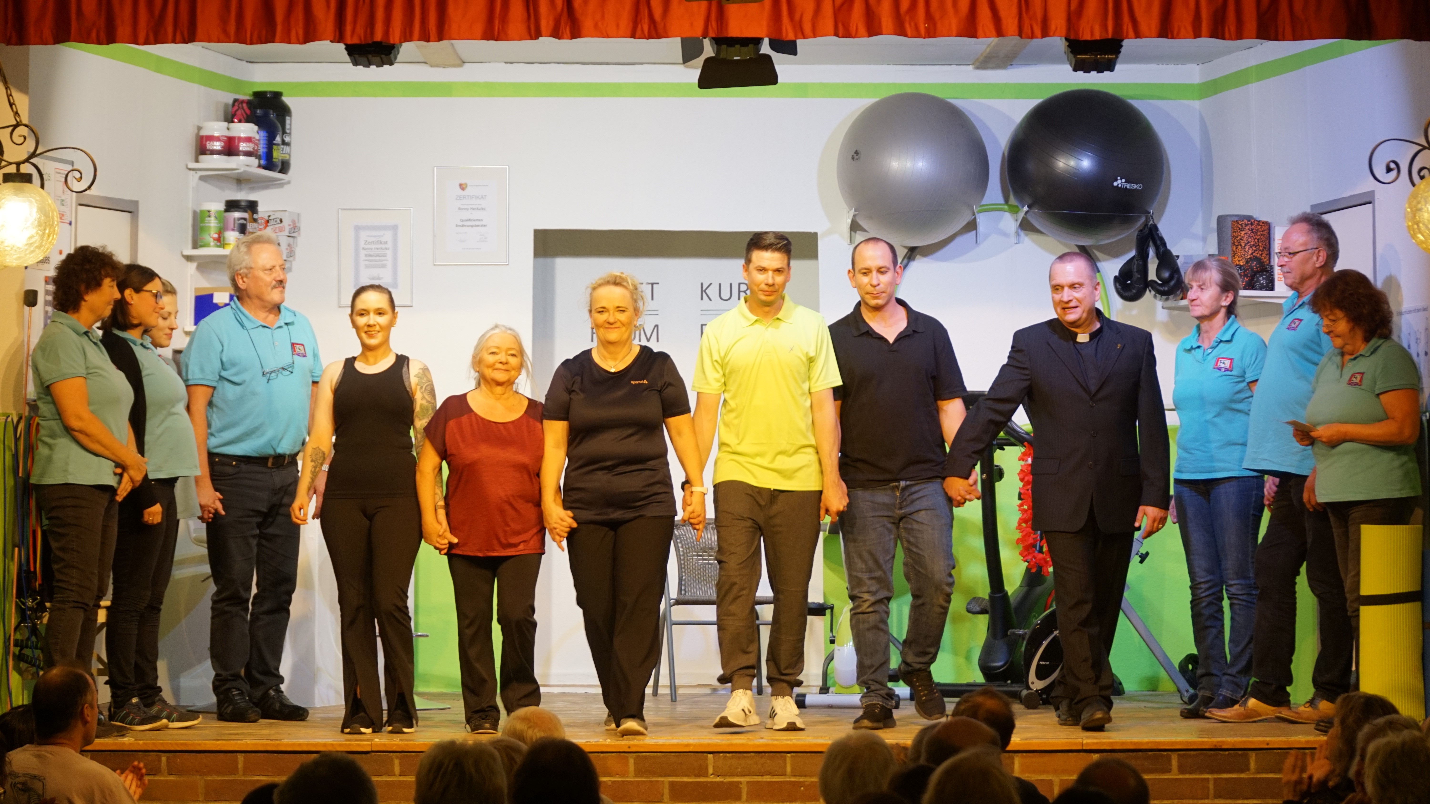 Die Crew des Novemberstücks „Bauch-Beine-Sahnetörtchen“ von Andreas Keßner, beim Schlussapplaus. (v.l.n.r. Tina Burger (Spielleitung/Inspizientin), Anja Klotz (Maske), Nicole Wolf (Maske), Günter Buchner (Inspizient), Barbara Wutz (Elfriede Henselein). Elisabeth Oberloher-Mehl (Pfarrersköchin Hildegard Amselhuber), Sabine Jörg (Renate Feldkirchner), Andreas Stürzer (Fitnessstudiobetreiber Ronny Herkules), Roland Dioguardi (Alois Kohnleitner/Bühnenbau), René Bormann (Pfarrer Sebastian), Rosi Spielberger (Souffleuse), Karl-Heinz Wurnitsch (Bühnenbau); Evi Wolf (Souffleuse).