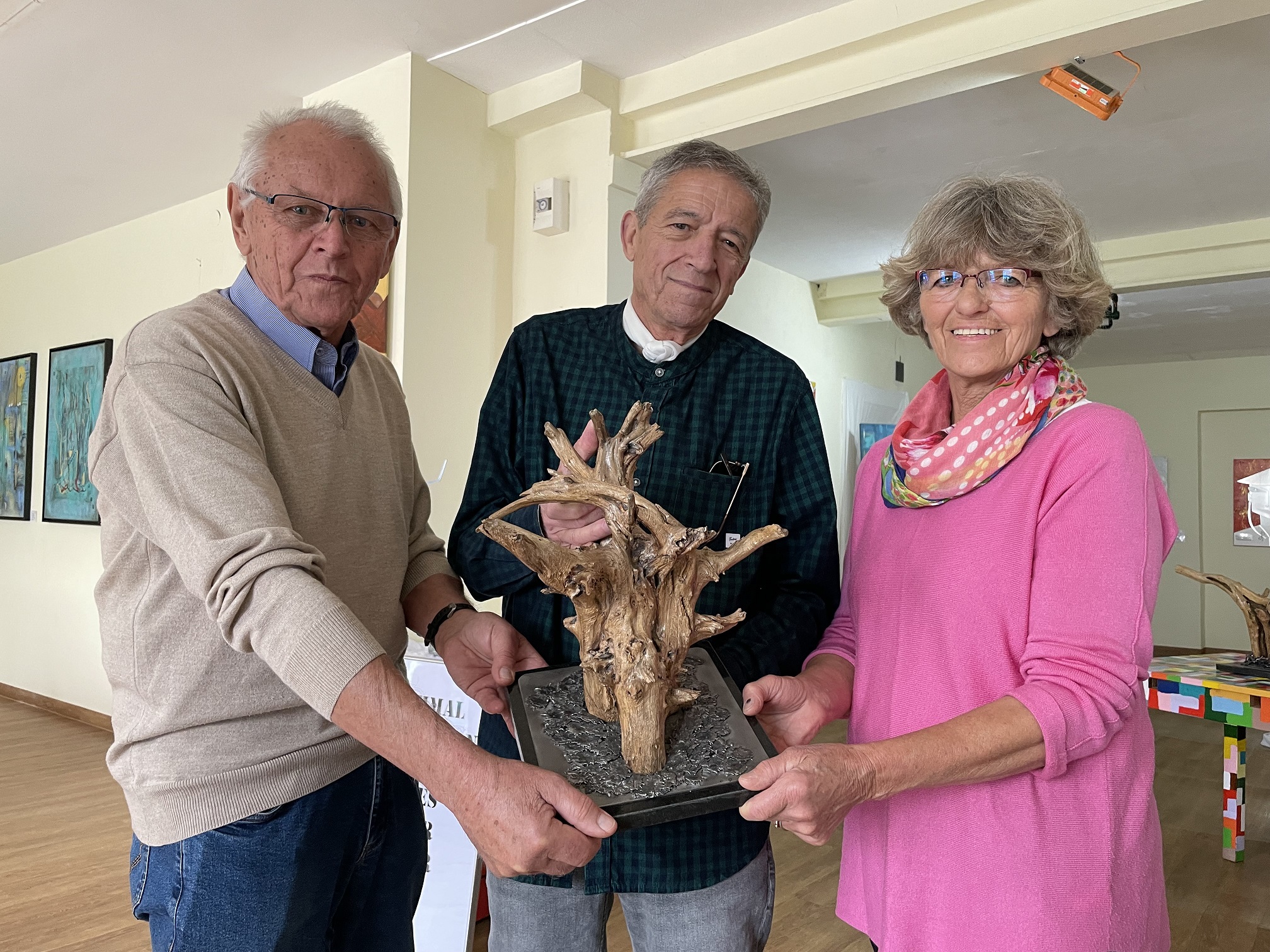 Helmut Blümel, Carmelo Rodriguez Oramas und Monika Glaser (von links) mit einer Holz-Skulptur mit Metalltropfen auf einer Marmorplatte von Oramas.